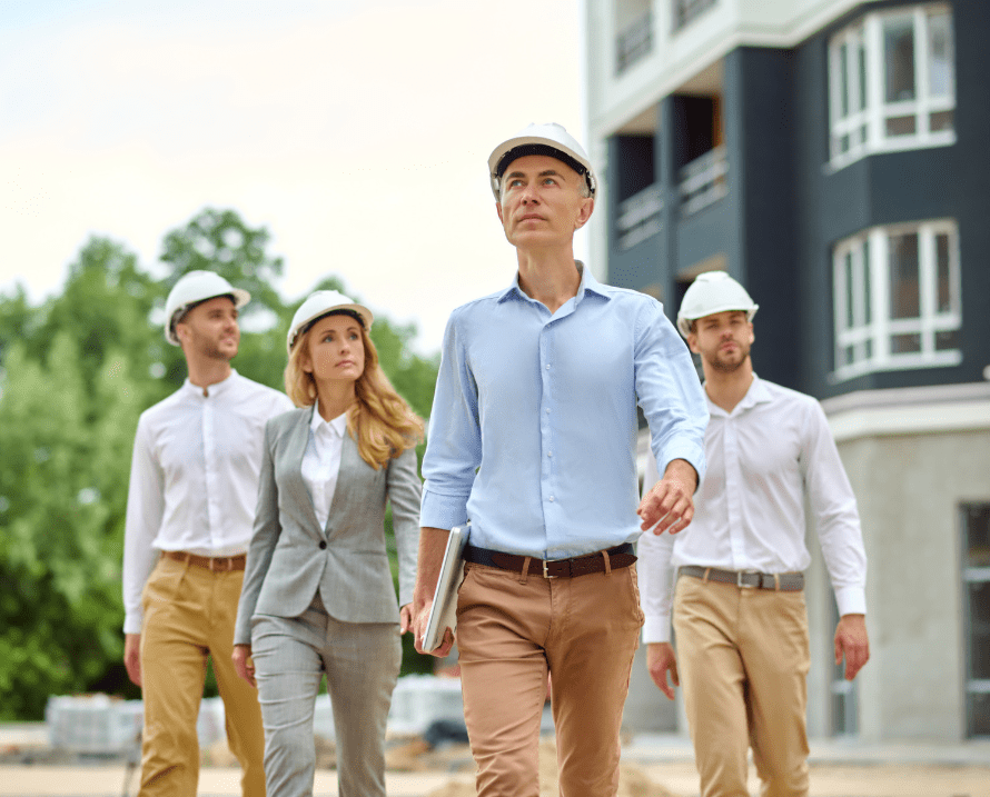 Group of real estate professionals and engineers inspecting a construction site in front of a modern residential building
